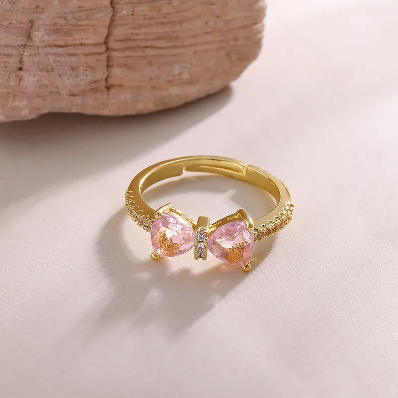 Gold ring with pink gemstones on a light background