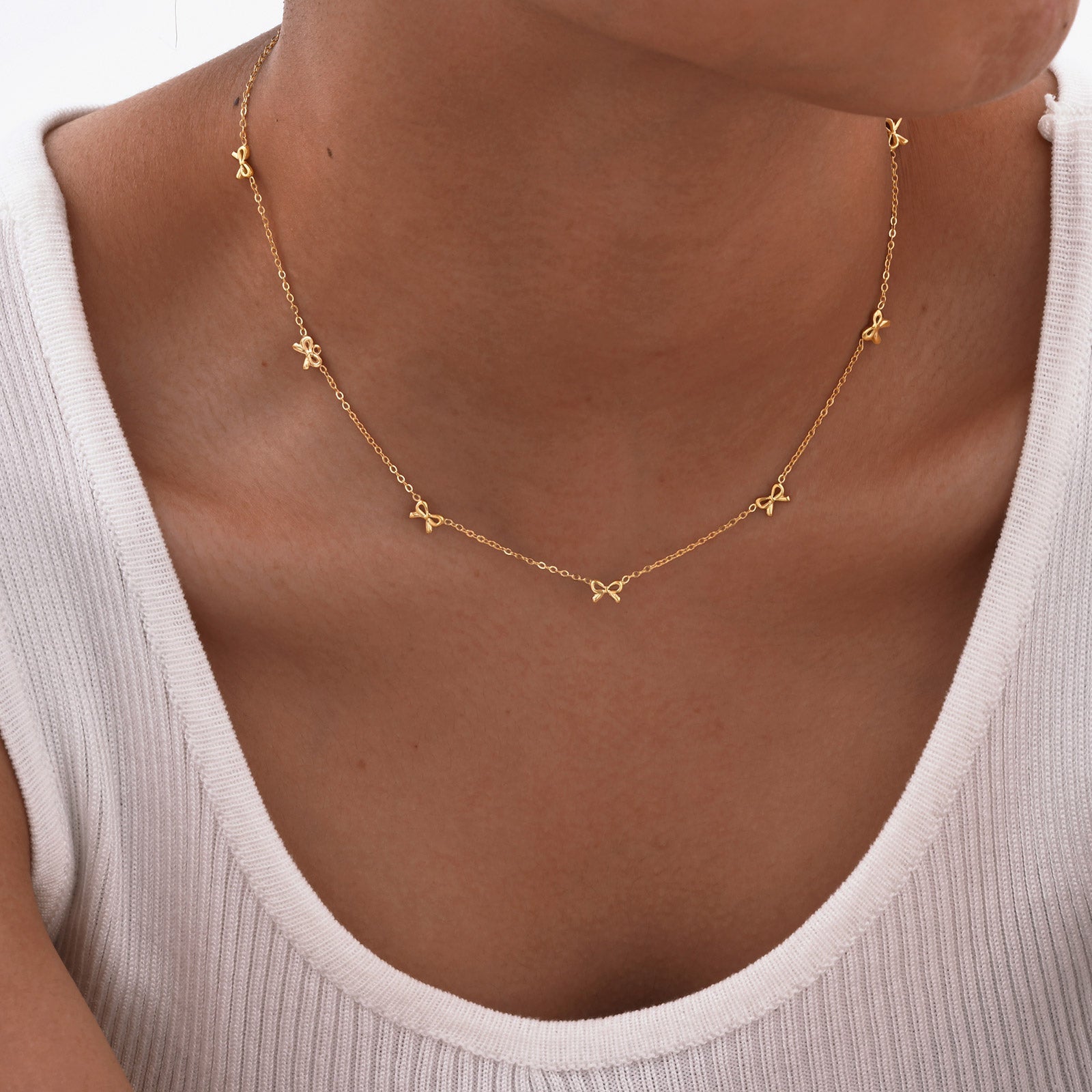 Gold necklace with star-shaped pendants on a person wearing a white top.