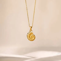 Gold necklace with a detailed pendant on a beige background
