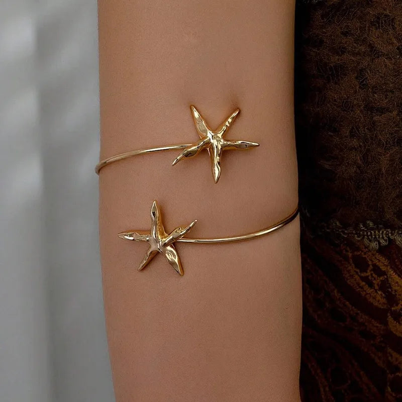 Gold starfish arm cuff bracelet worn on upper arm, ocean-inspired beach jewelry, elegant coastal statement accessory for women
